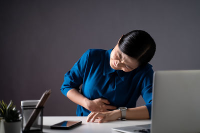 Woman using mobile phone while sitting on table