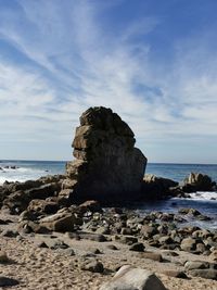 Rock formation on beach against sky