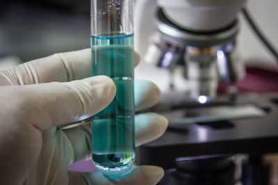 Close-up of cropped hand holding liquid in test tube in laboratory