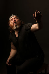 Midsection of man sitting against black background