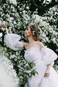 A beautiful delicate elegant young woman bride in a wedding dress walks in a blooming spring park