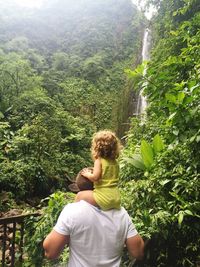 Rear view of father and daughter in forest