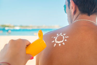 Rear view of woman on beach against sky