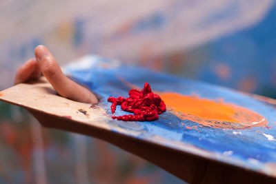 Close-up of hand holding red color on pallette