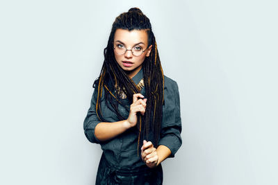 Portrait of young woman standing against white background