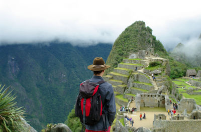 Rear view of man looking at machu picchu ruins on mountain against sky