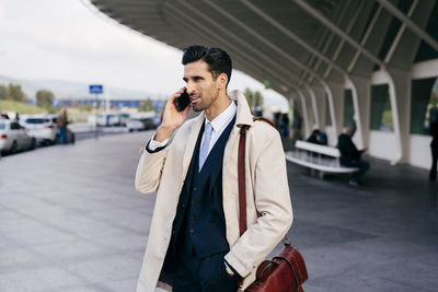 Young man using mobile phone while standing on bus