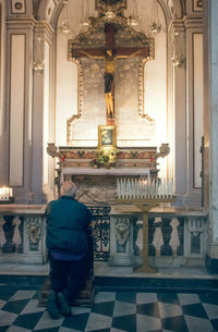 Rear view of man walking in temple against building