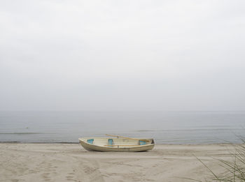 Boat moored on beach against sky