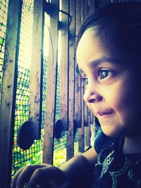 Close-up of cute girl looking away through window