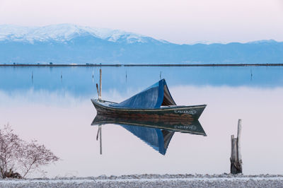 Boat in lake against mountains during winter