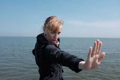 Young woman showing stop gesture against sea