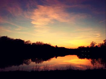 Silhouette trees by lake against sky during sunset