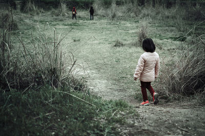 Rear view of woman walking on field