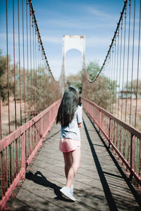 Rear view of woman walking on footbridge