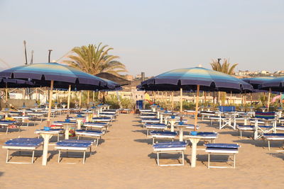 Empty chairs on beach against clear sky