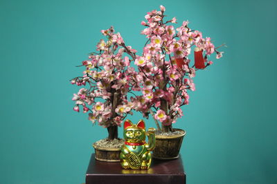 Close-up of flowering plant in vase against blue background