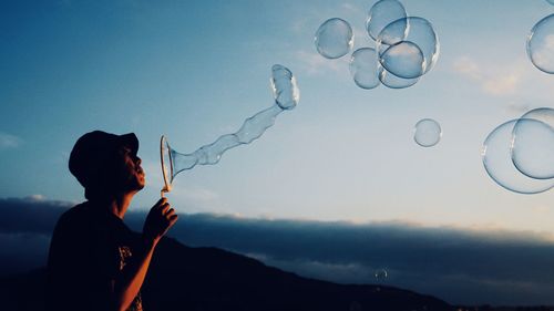 Man blowing bubbles against blue sky