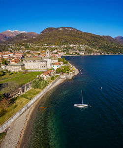 Aerial view of townscape by sea against blue sky