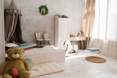 A large stuffed bear toy in the interior of a children's room with a teepee. wooden horse gurney