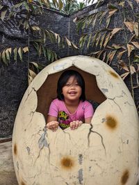 A girl standing inside a replica of dinosaur egg.