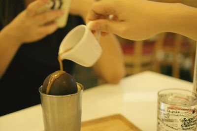 Close-up of hand pouring drink in cup