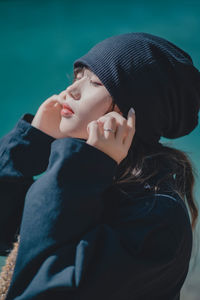 Portrait of young woman standing against black background