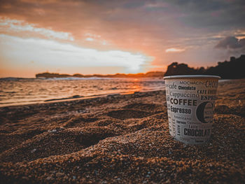 Close-up of text on beach against sky during sunset