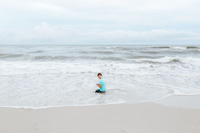 Boy on beach against sky