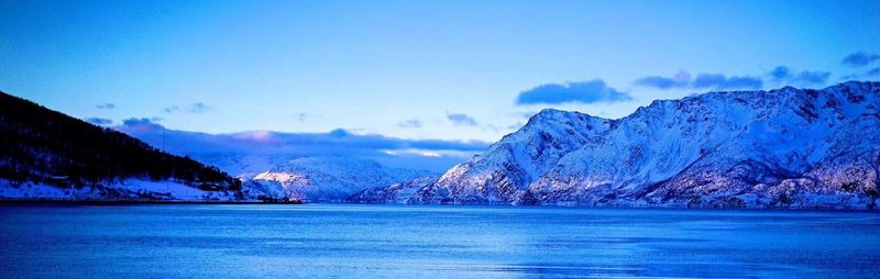 Scenic view of lake and mountains against blue sky