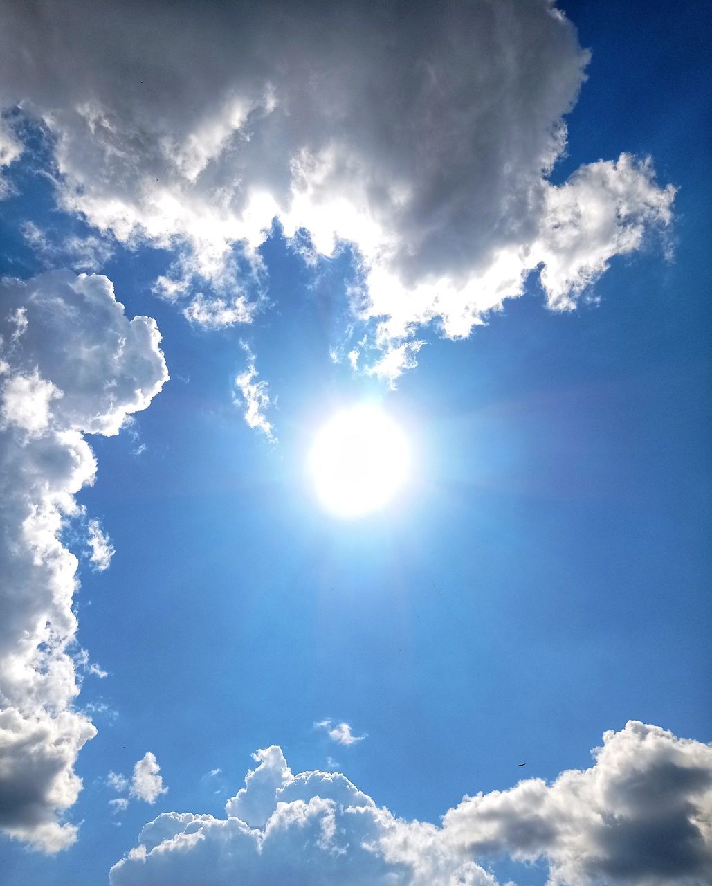 LOW ANGLE VIEW OF SUN SHINING ON CLOUDY SKY