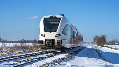 Train on railroad tracks against sky during winter