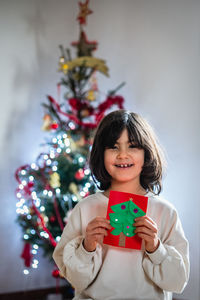 Portrait of young girl holding christmas self made postcard