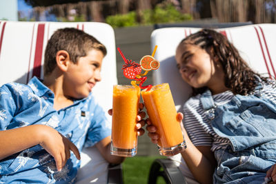 Two funny kids making a toast with orange juice