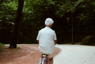 Rear view of man riding bicycle on road