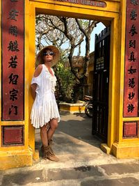 Full length of woman wearing hat standing at temple entrance