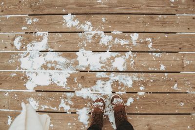 Low section of person on boardwalk during winter