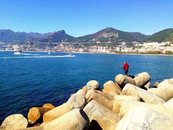 Man fishing in sea against blue sky