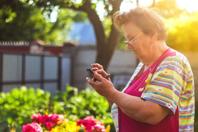 A 65-year-old woman looks at the phone in the yard grandma is learning how to use the telephone 