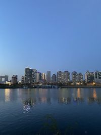 Scenic view of river and buildings against clear sky