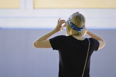 Rear view of woman standing against wall