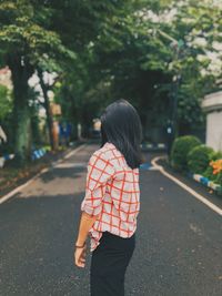 Rear view of woman standing on road in city