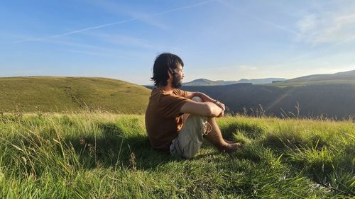 Rear view of woman standing on field against sky