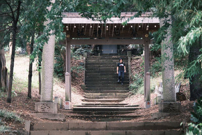 Rear view of woman standing by staircase against building