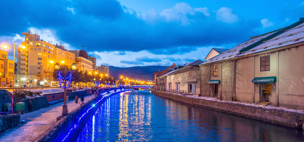 Canal amidst illuminated buildings in city at night