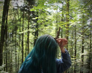 Woman holding stick on head in forest