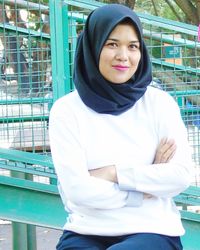 Portrait of young woman standing against building