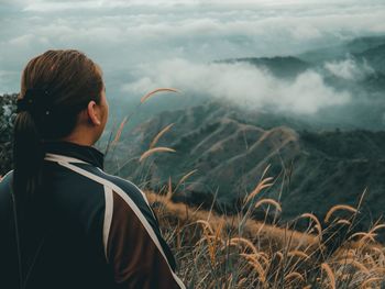 Rear view of woman standing on mountain against sky