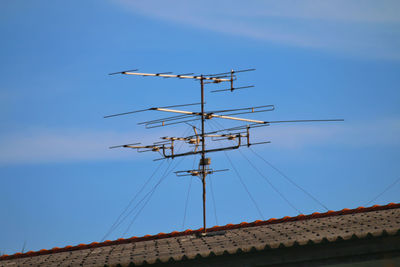 Low angle view of communications tower on building against sky