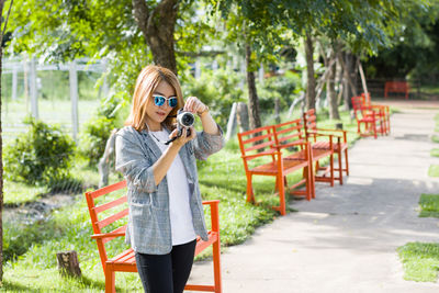 Woman with camera standing in park